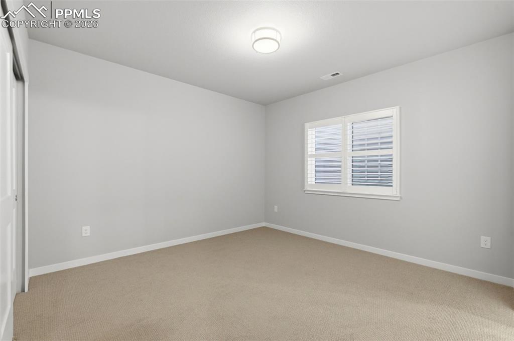 Image 34 of 48: Spacious finished basement room with large window, neutral paint, and plush