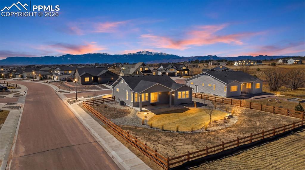 Image 39 of 48: Back of home at dusk showcasing the covered deck, large windows, and beauti