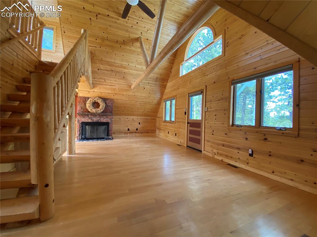Image 14 of 36: Living room featuring wooden walls, high vaulted ceiling with exposed beams