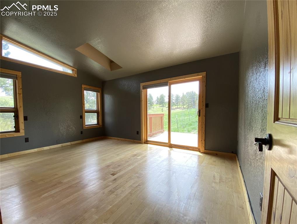 Image 9 of 36: The primary bedroom featuring wood floors, lofted ceiling, with plenty of n