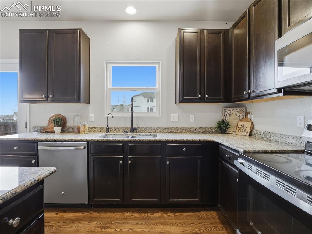 Image 13 of 45: Kitchen featuring stainless steel appliances, light stone counters, dark wo