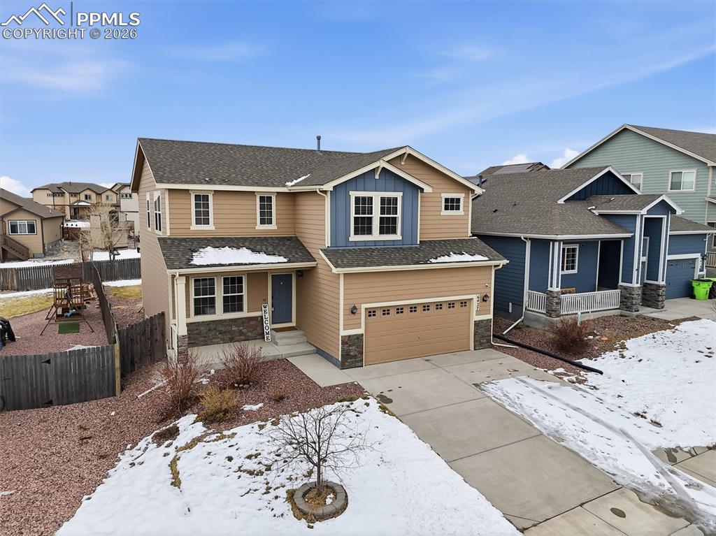 Image 44 of 45: View of front of house with a porch, stone siding, concrete driveway, an at