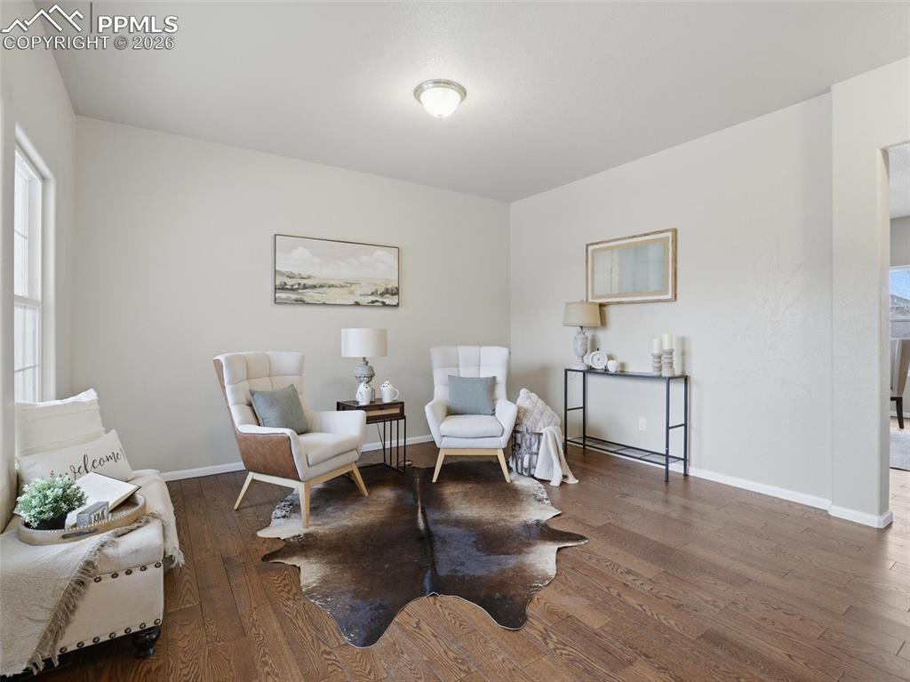 Image 5 of 45: Living area with dark wood-type flooring and baseboards