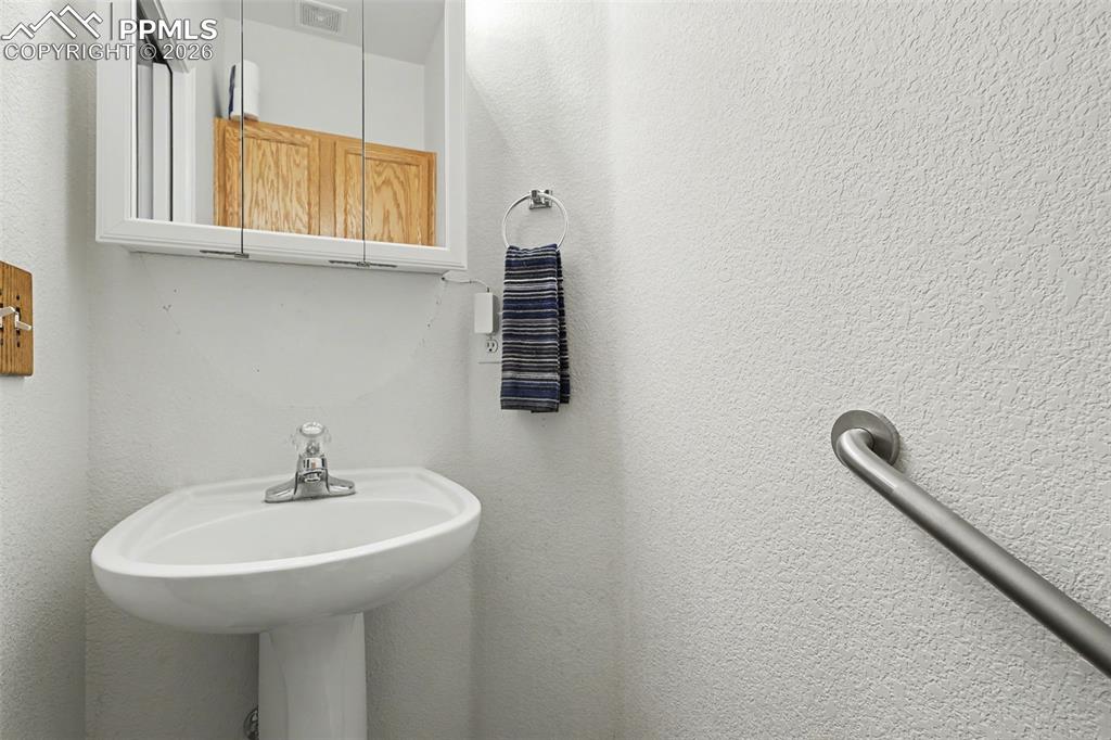 Image 10 of 15: Main level half bath has toilet & pedestal sink