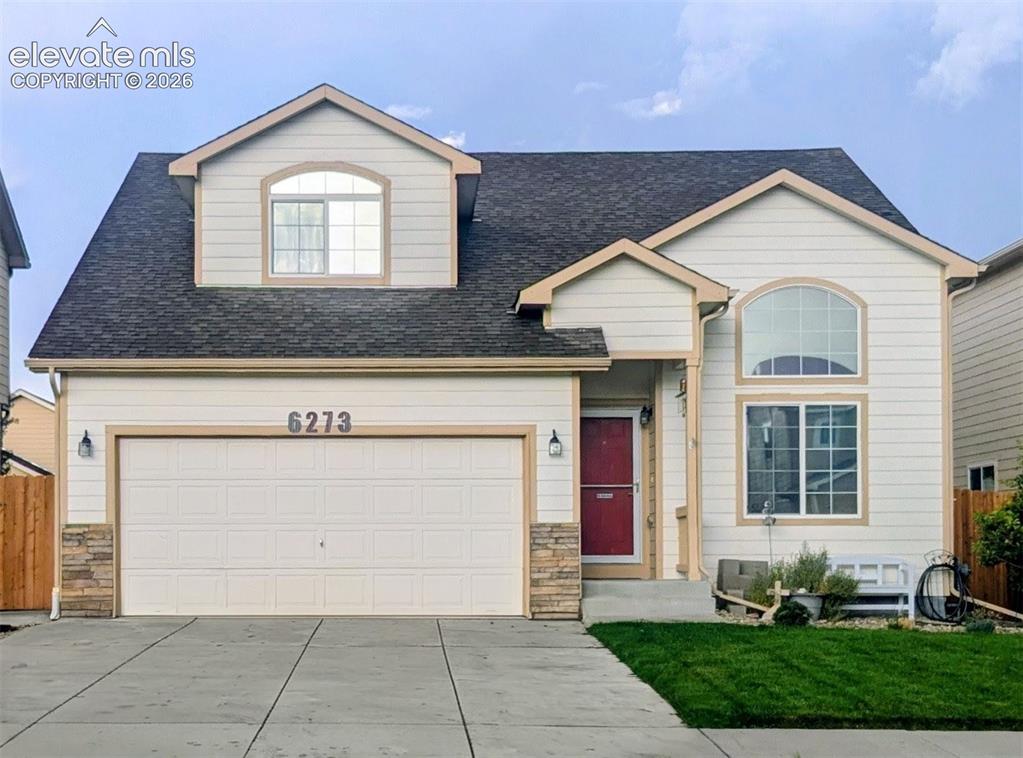 Image 1 of 33: Cream-colored exterior featuring a prominent two-car garage with stone vene