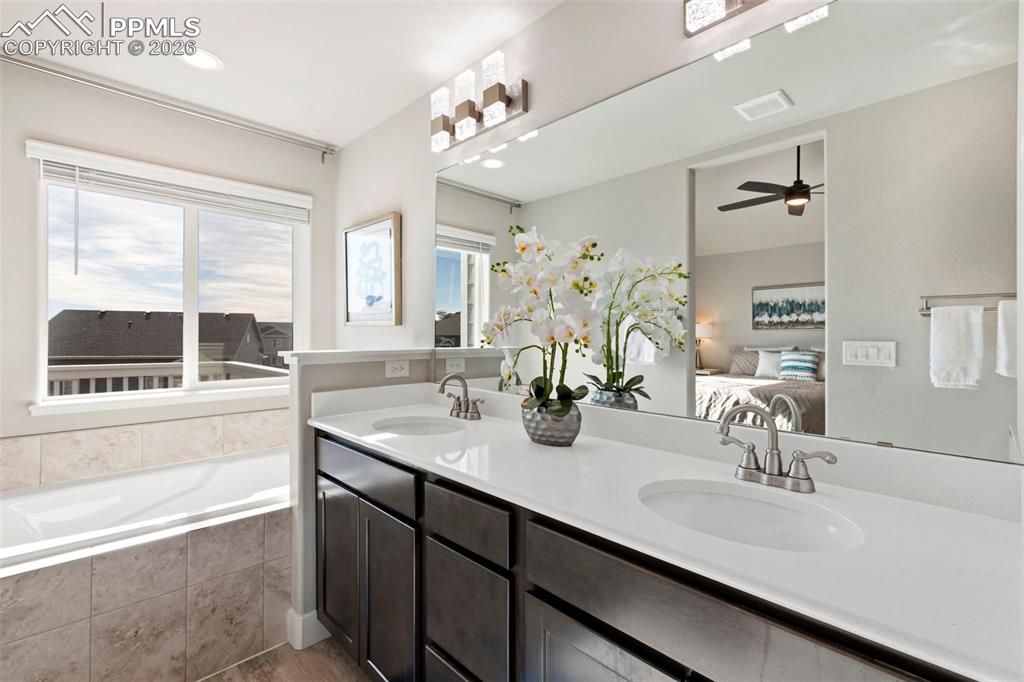 Image 11 of 45: Bathroom featuring connected bathroom, a bath, double vanity, a ceiling fan