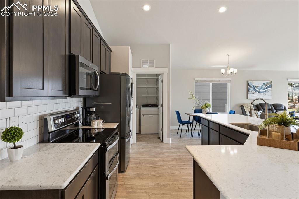 Image 17 of 45: Kitchen with stainless steel appliances, washer / clothes dryer, light ston