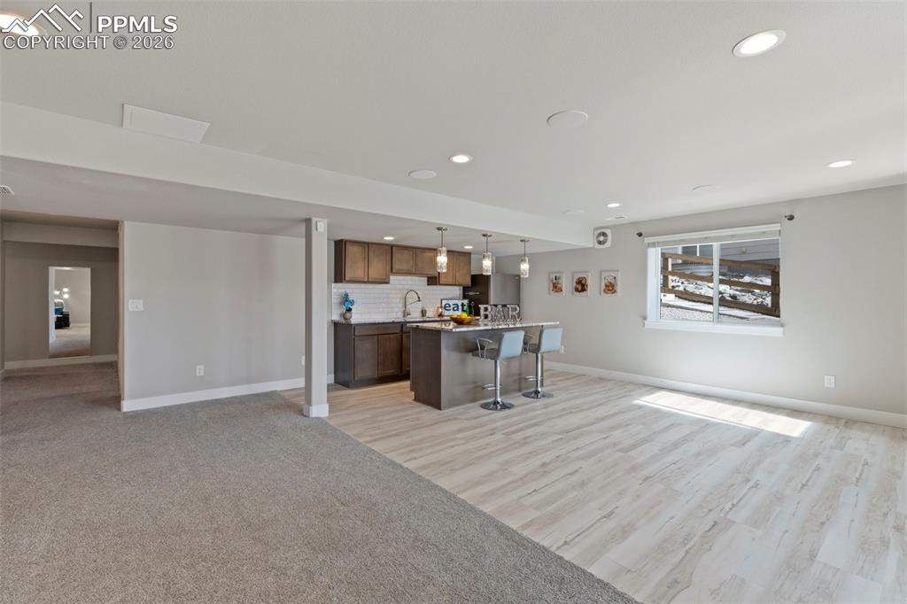 Image 29 of 45: Basement Kitchenette with open floor plan, a breakfast bar area, a kitchen 