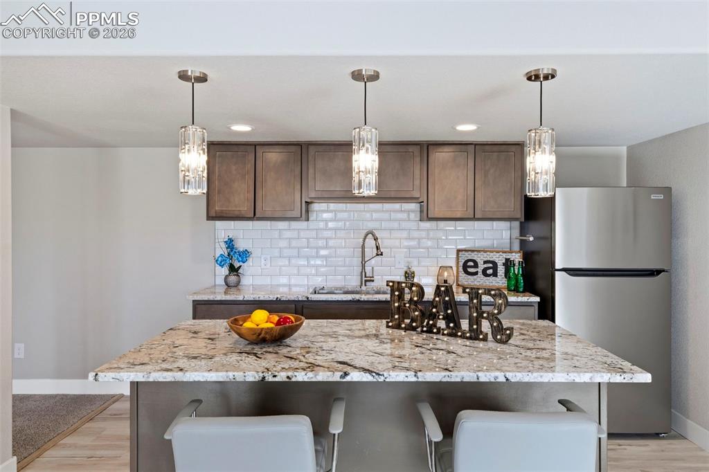 Image 30 of 45: Basement Kitchenette/Bar with freestanding refrigerator, a center island wi