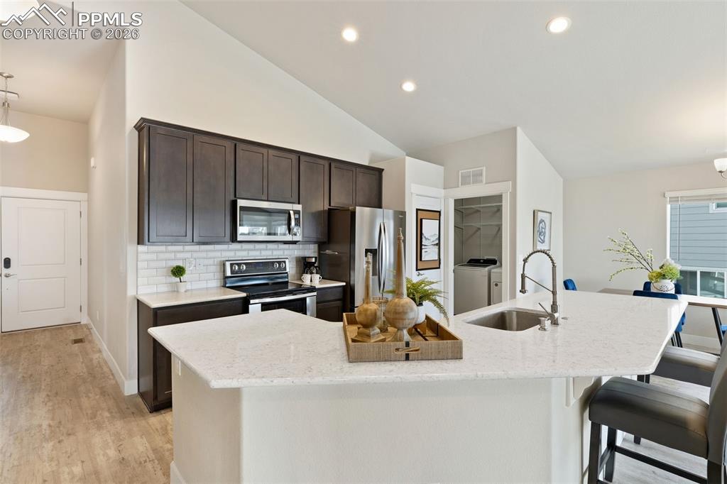 Image 8 of 45: Kitchen featuring hanging light fixtures, lofted ceiling, stainless steel a