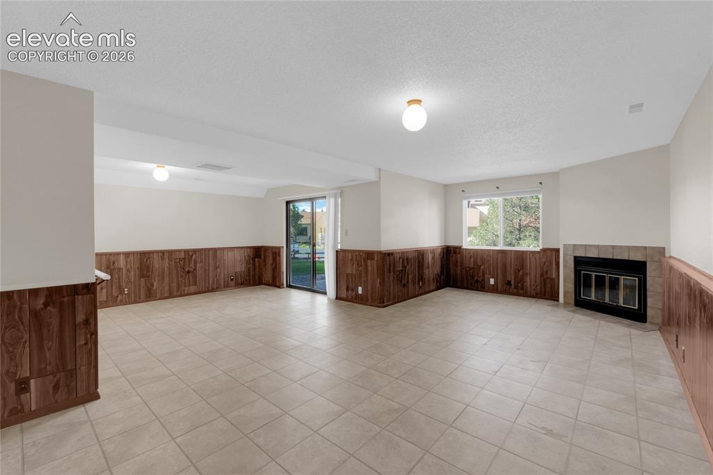 Image 22 of 33: Flex space in basement with a fireplace and walk-out to patio.