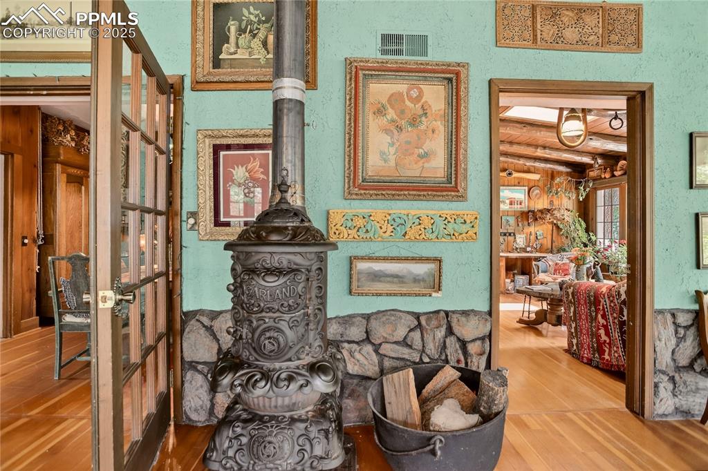 Image 18 of 41: Access to den & dining room. Original wood stove.
