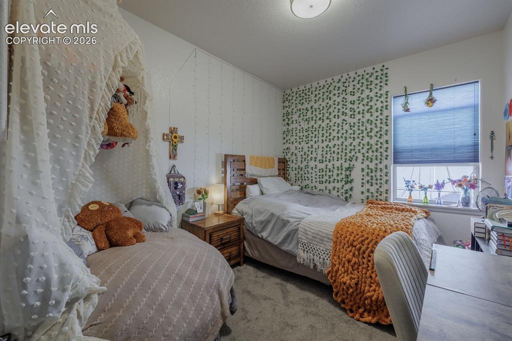Image 14 of 16: Carpeted room featuring a window with cellular blinds, a textured accent wa