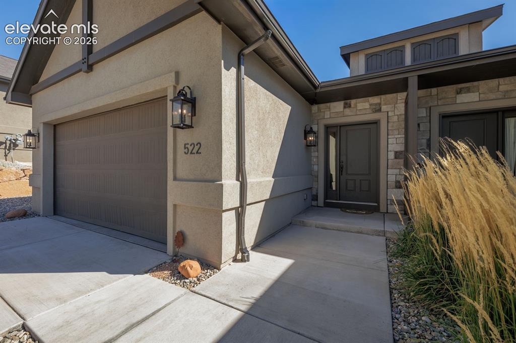 Image 3 of 16: Stucco exterior with stone accents, dark trim, and a prominent garage door