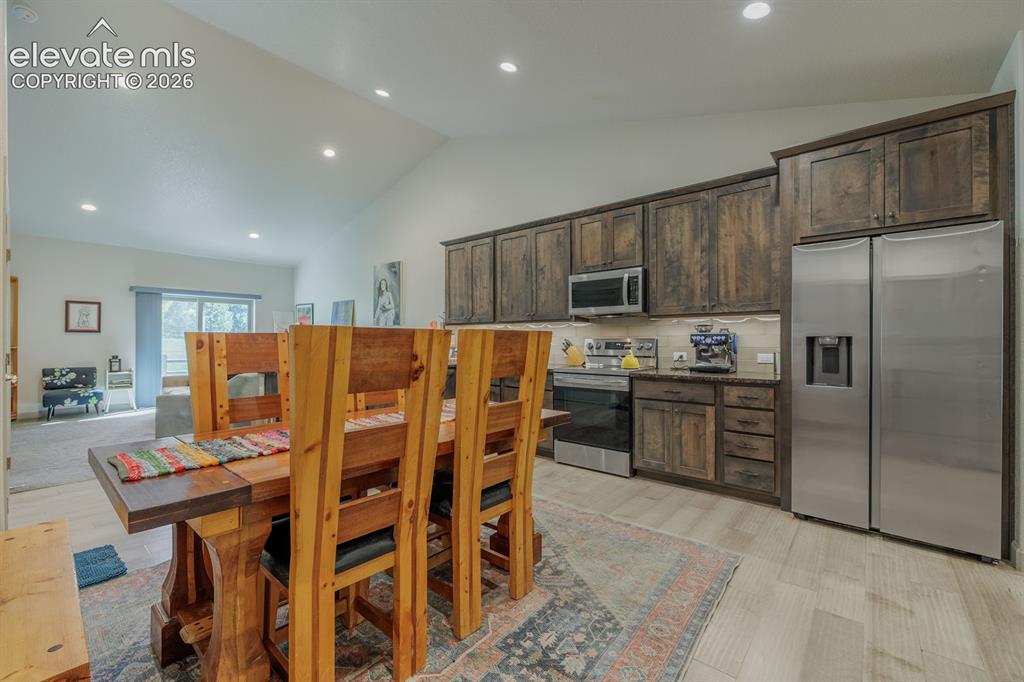 Image 5 of 16: Vaulted ceiling with recessed lighting, wood-finish flooring, wood cabinetr
