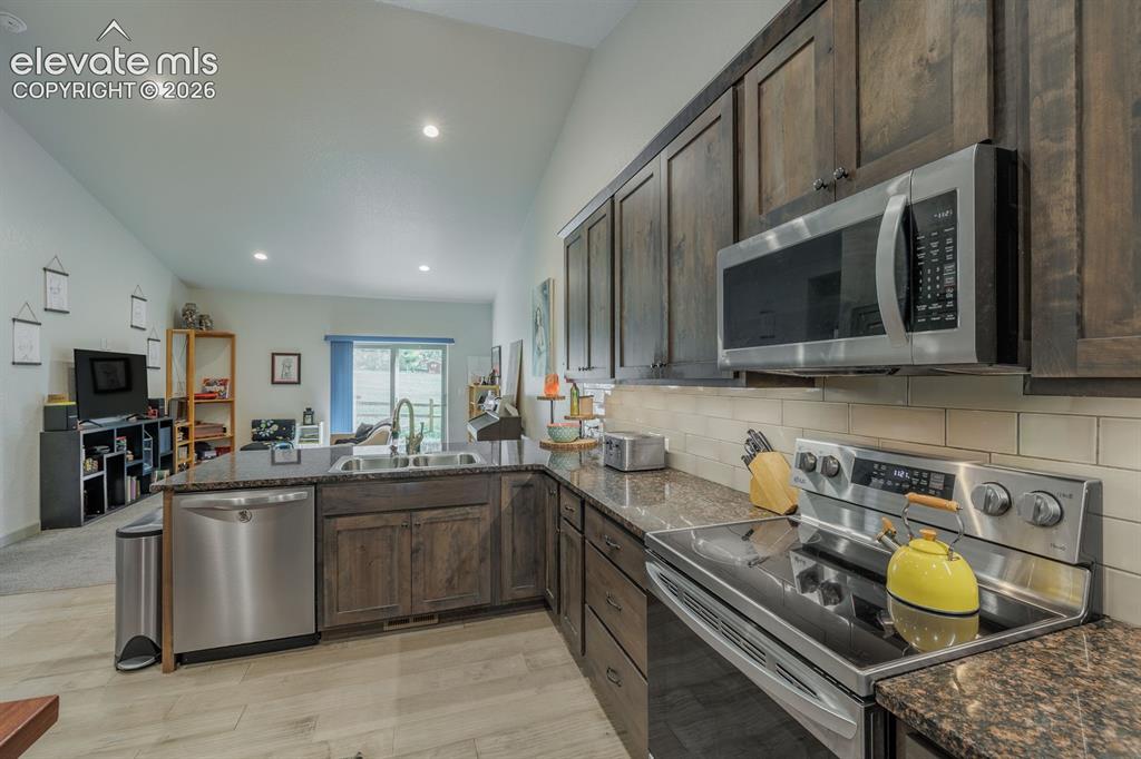 Image 6 of 16: Kitchen featuring dark wood-finish cabinetry, stainless steel appliances, s