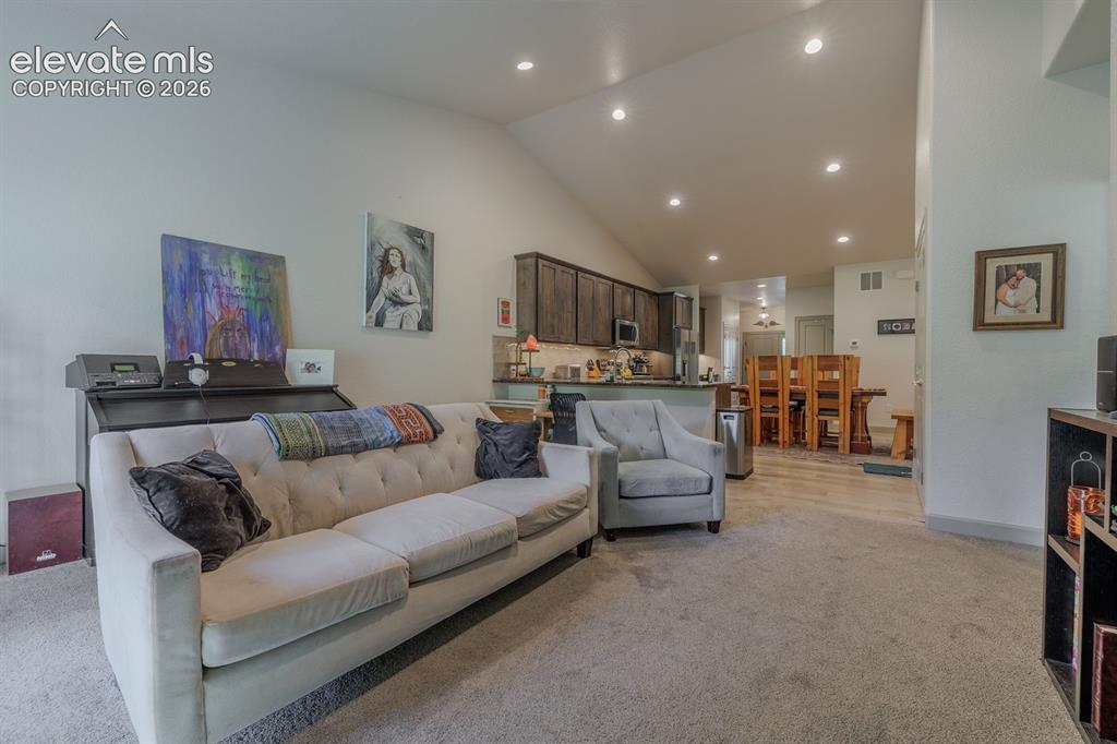 Image 8 of 16: Vaulted ceiling with recessed lighting, carpeting, wood-finish flooring, an