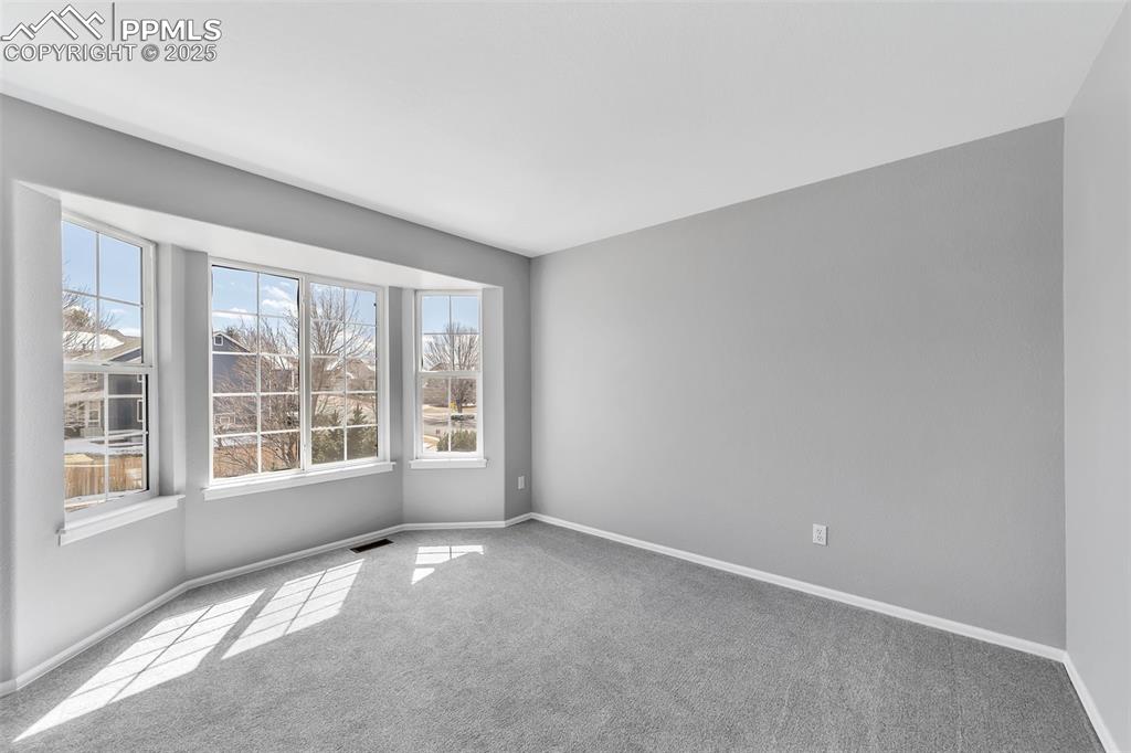 Image 31 of 49: Secondary bedroom (1 of 3 on upper level) with bay window.
