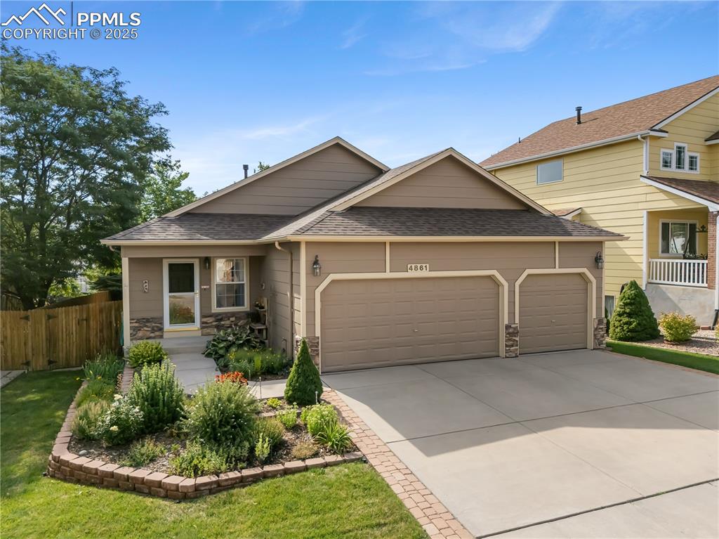 Caption: View of front of home featuring stone siding, roof with shingles, an attached garage, and driveway