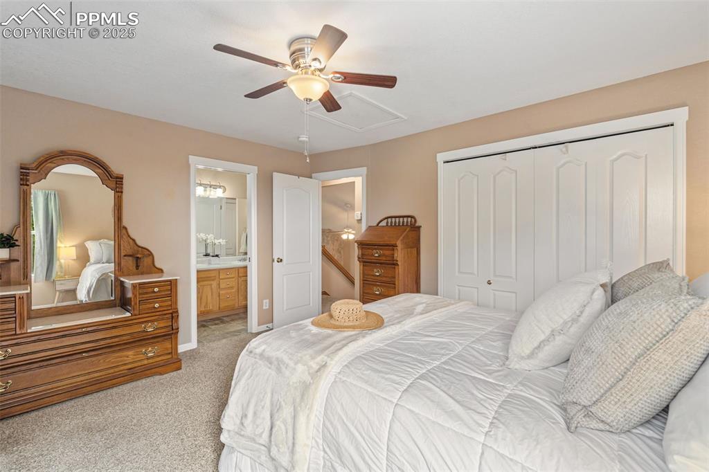 Image 13 of 36: Bedroom with light carpet, a ceiling fan, a closet, and connected bathroom