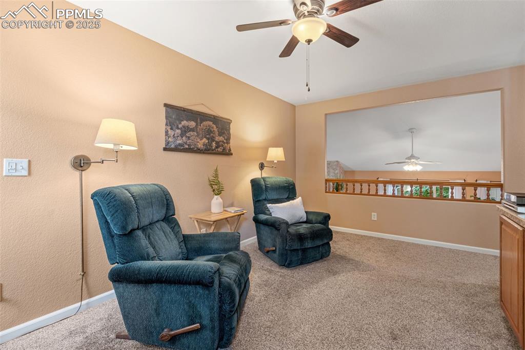 Image 17 of 36: Living area with a ceiling fan and light carpet