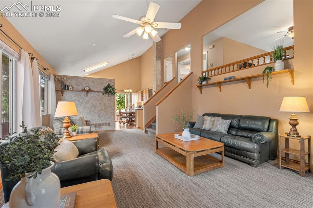 Image 2 of 36: Living area featuring high vaulted ceiling, ceiling fan, carpet flooring, a