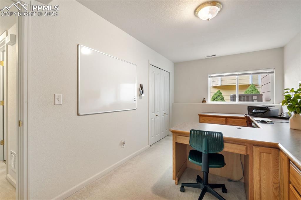 Image 23 of 36: Home office with light carpet and baseboards