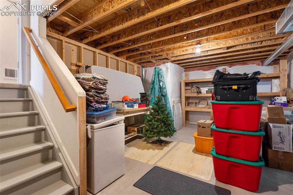 Image 26 of 36: Unfinished basement with white refrigerator