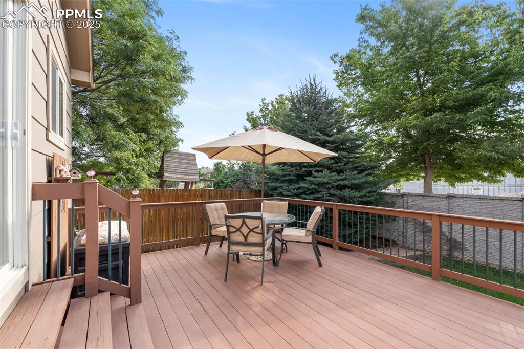 Image 27 of 36: Wooden terrace featuring outdoor dining space and a fenced backyard