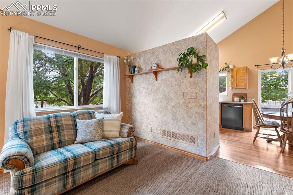 Image 4 of 36: Sitting room featuring vaulted ceiling, a chandelier, and light wood finish