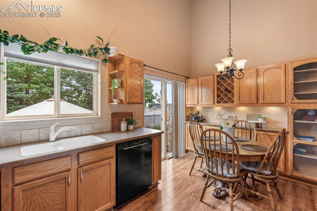 Image 7 of 36: Kitchen featuring pendant lighting, black dishwasher, light wood-style floo