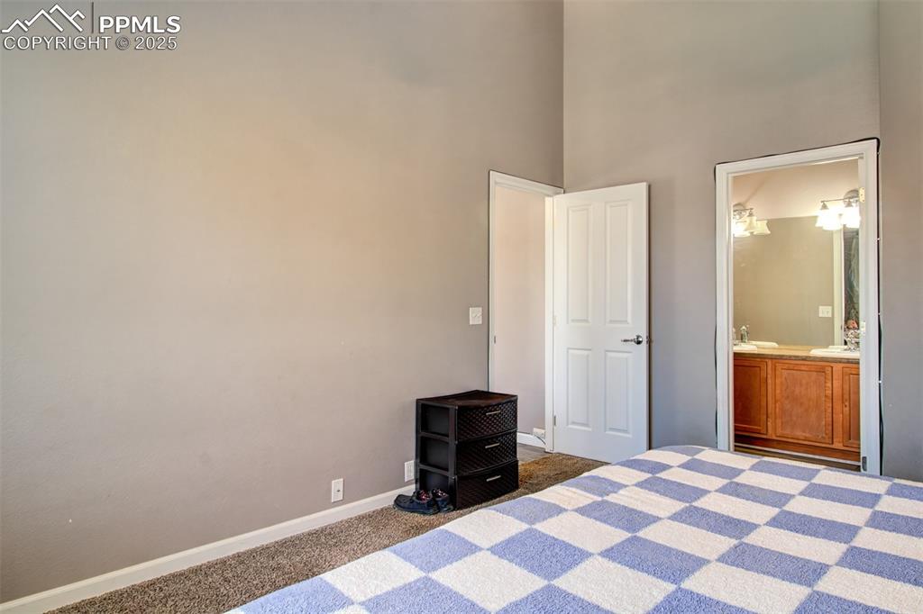 Image 12 of 21: Unfurnished bedroom featuring dark carpet, ensuite bath, and a towering cei