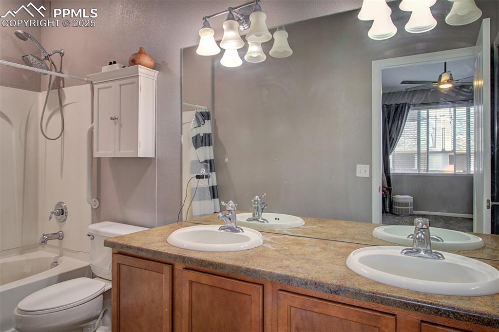 Image 14 of 21: Full bath with a chandelier, double vanity, and shower / tub combo with cur