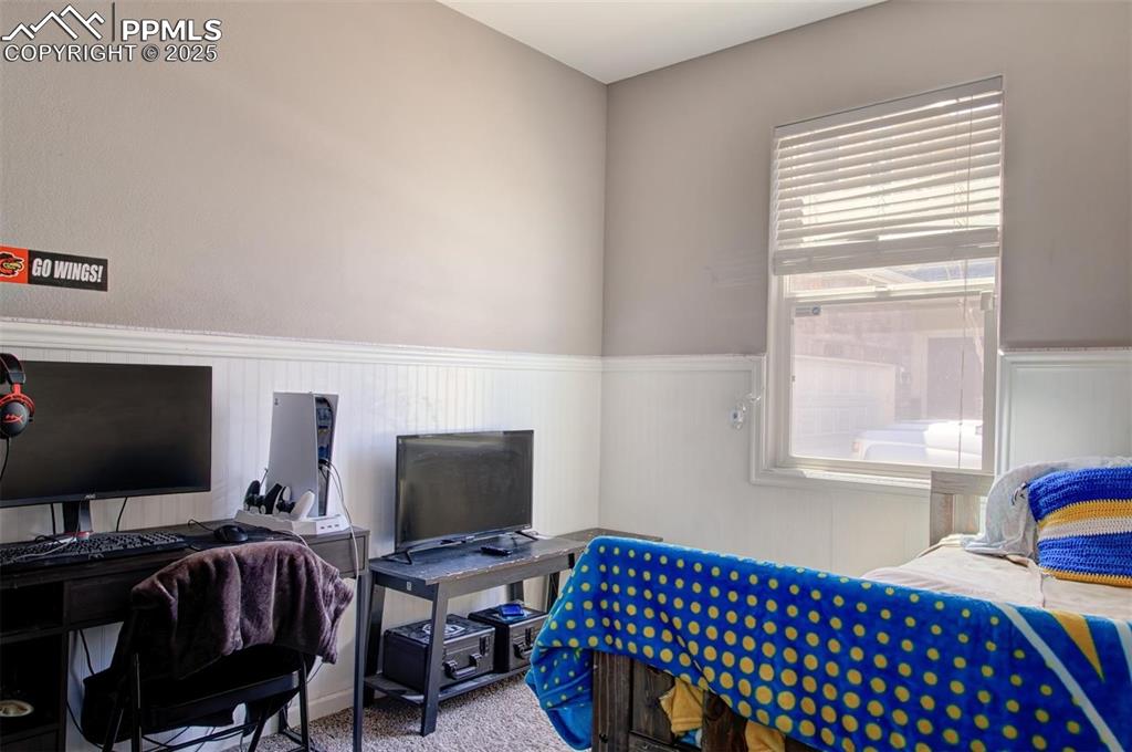 Image 15 of 21: Carpeted bedroom with a wainscoted wall and a desk