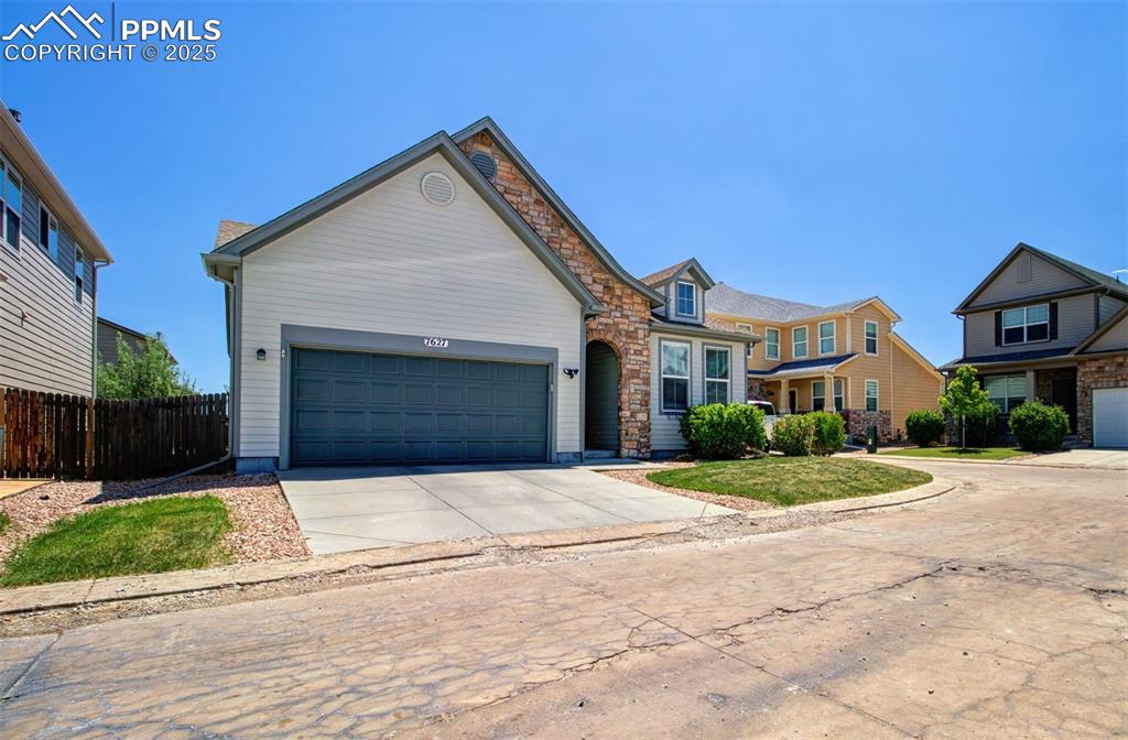 Image 2 of 21: View of front of home featuring concrete driveway, stone siding, and an att