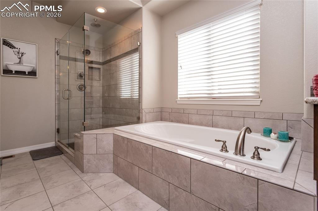 Image 25 of 50: Luxurious deep soaking tub and frameless glass shower