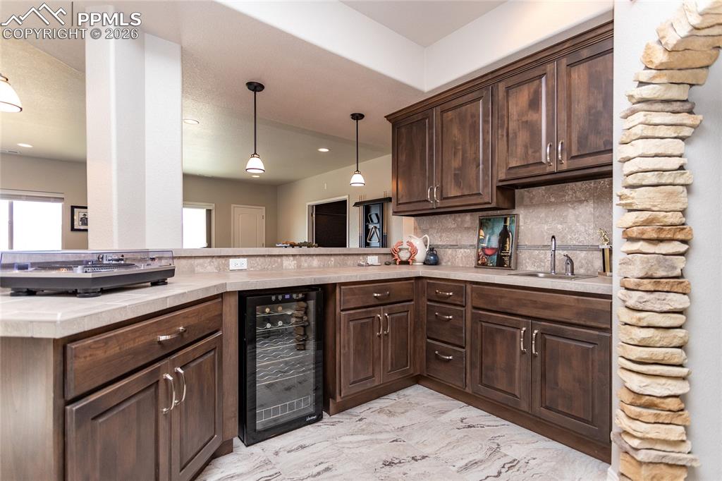 Image 30 of 50: Wet bar with wine fridge and space to add another larger refrigerator