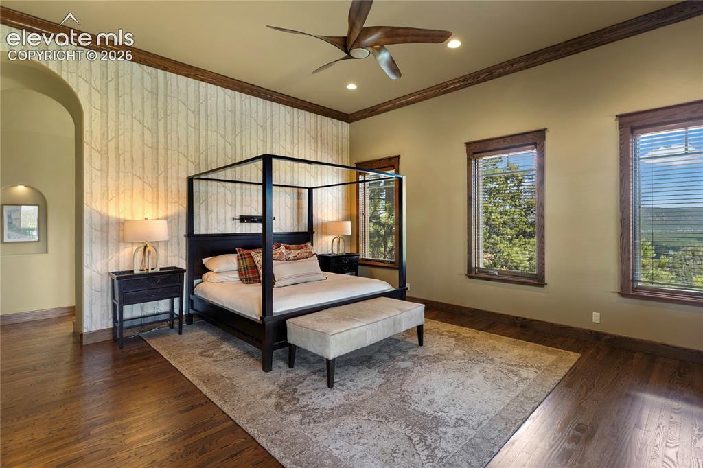 Image 13 of 36: Spacious room featuring wood-finish flooring, an arched doorway, and two wi