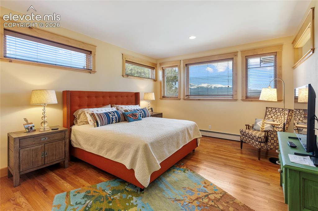 Image 15 of 36: Bedroom featuring wood-finish flooring and multiple windows with wood trim