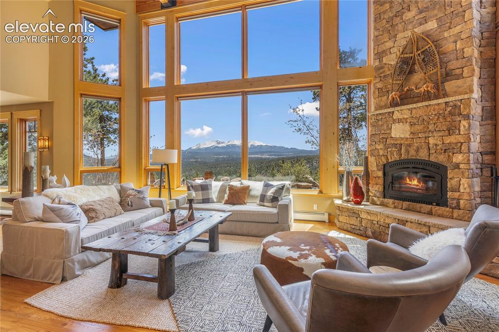 Image 2 of 36: Great room featuring a striking stone fireplace and expansive windows that