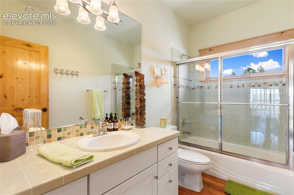 Image 21 of 36: Bathroom featuring a single vanity with tile countertop, integrated sink, a