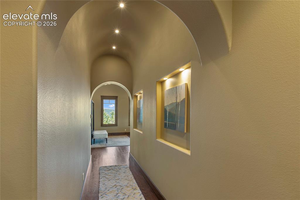 Image 26 of 36: Arched hallway featuring recessed lighting and built-in wall niches