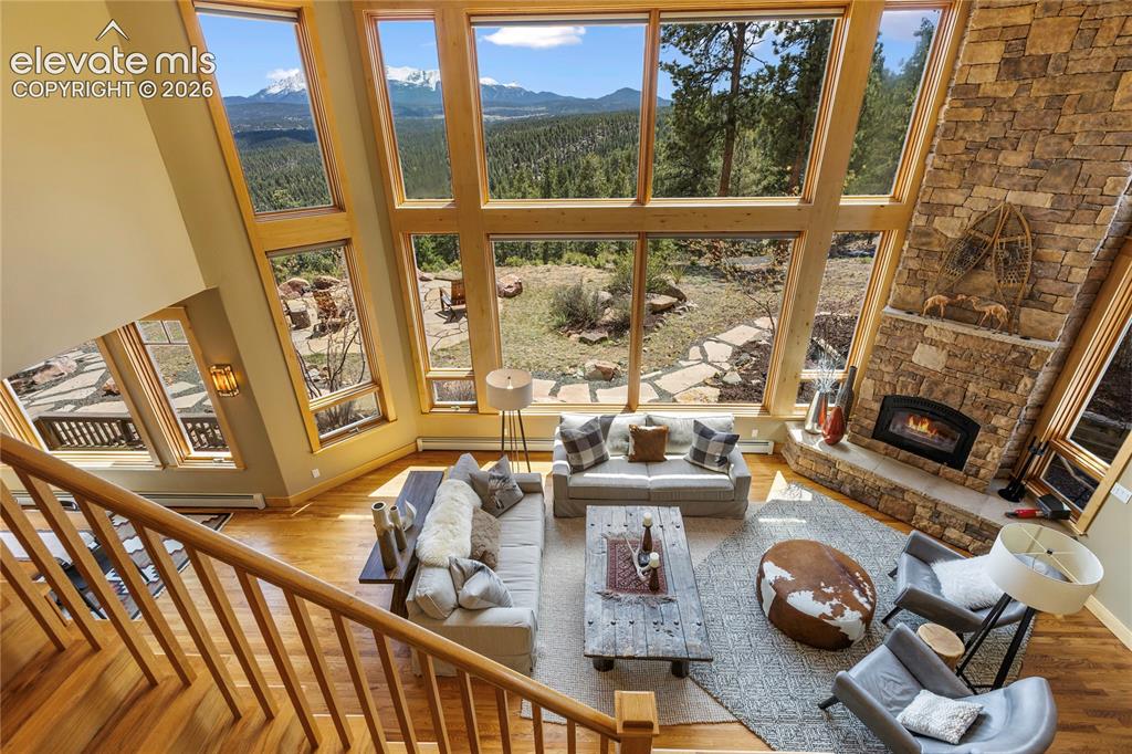 Image 3 of 36: Expansive living area featuring a floor-to-ceiling stone fireplace, large w
