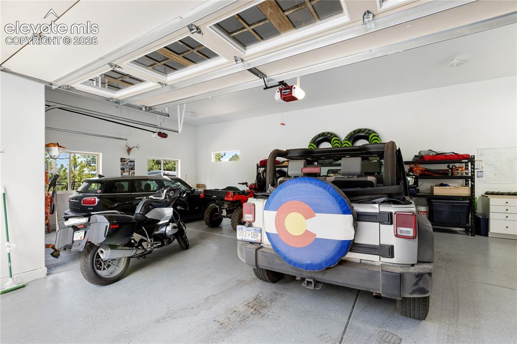 Image 30 of 36: Oversized three-car garage with high ceilings and ample room for vehicles,