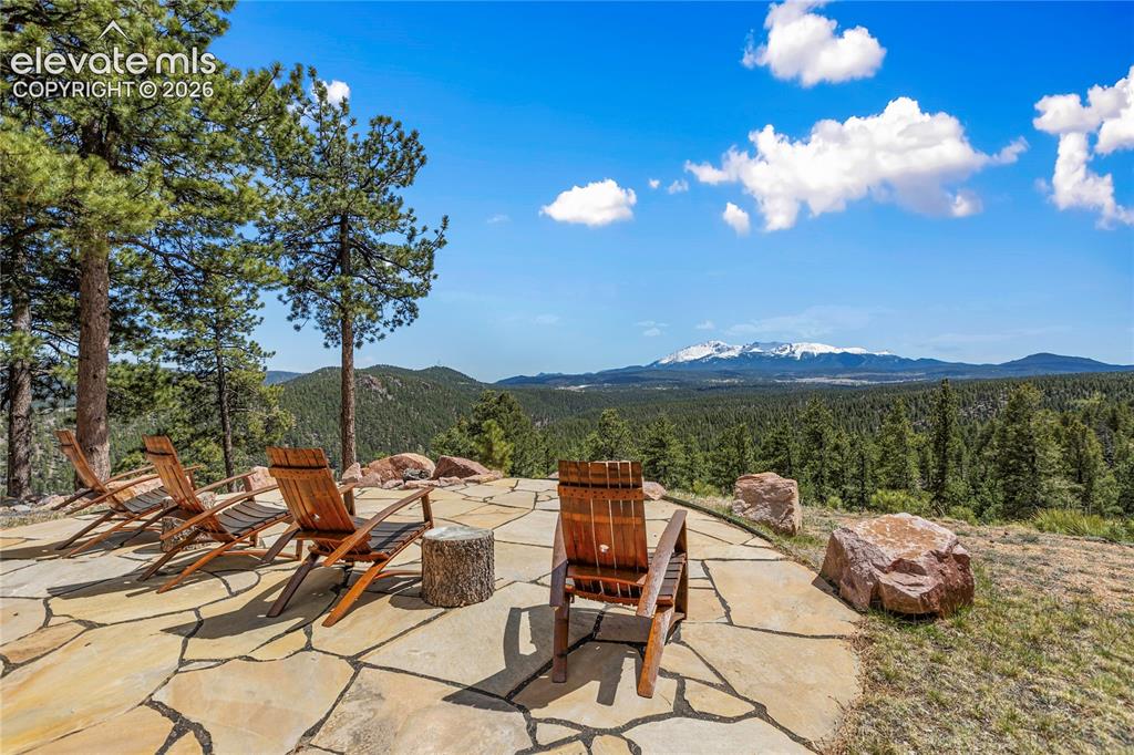 Image 31 of 36: Expansive flagstone patio with natural rock accents, surrounded by mature p