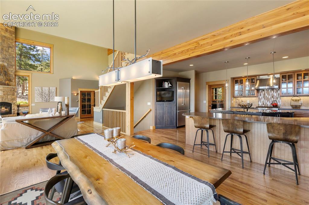 Image 8 of 36: Open-concept living space featuring a stone fireplace, wood-finish flooring
