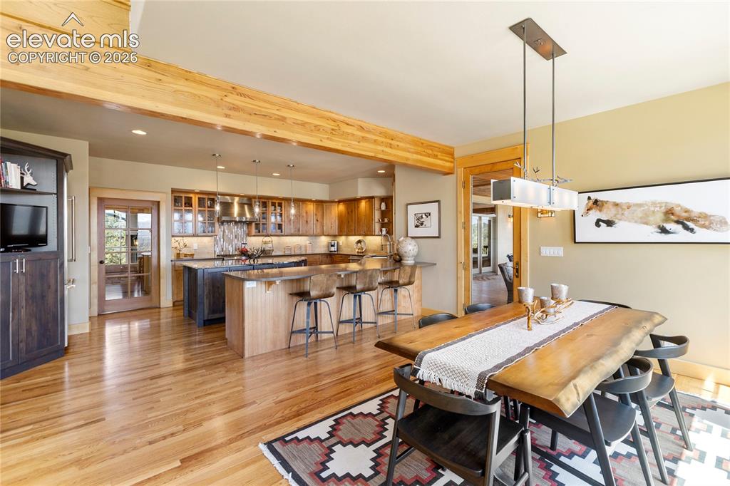 Image 9 of 36: Dining area with wood-finish flooring featuring a linear chandelier