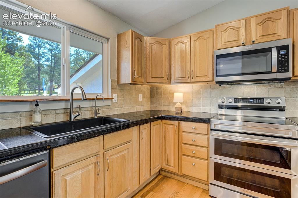 Image 15 of 50: Kitchen featuring hardwood flooring, natural wood cabinetry, dark counterto