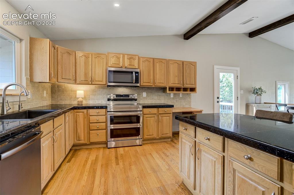 Image 16 of 50: Kitchen featuring a black sink with a gooseneck faucet, black countertops,