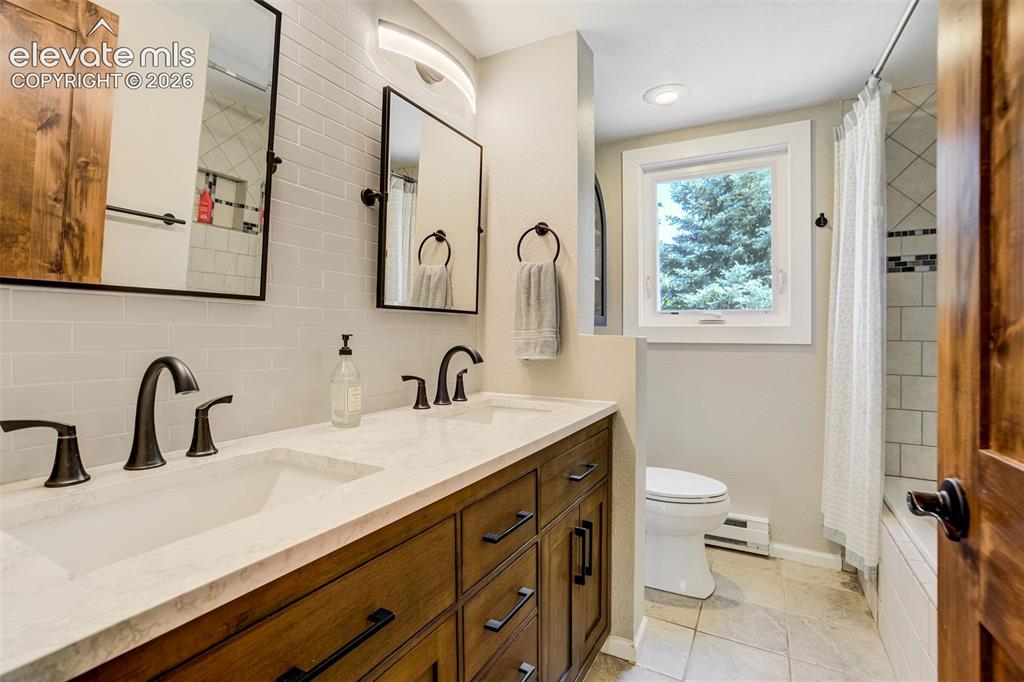 Image 17 of 50: Kitchen featuring wood cabinetry, dark countertops, tile backsplash, and st